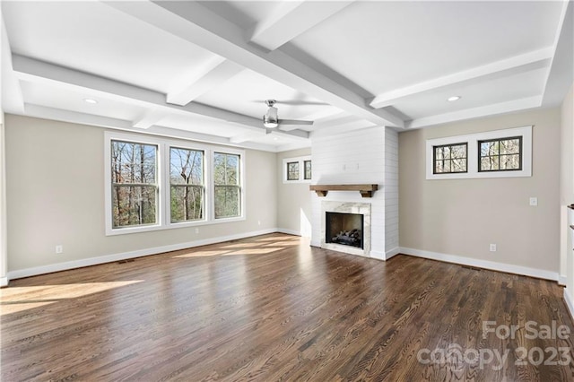 unfurnished living room featuring ceiling fan, beam ceiling, a large fireplace, and dark wood-type flooring