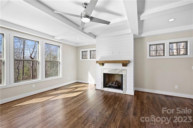 unfurnished living room featuring dark wood-type flooring, beamed ceiling, ceiling fan, coffered ceiling, and a large fireplace