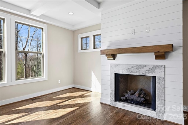 unfurnished living room with beam ceiling, a fireplace, and dark wood-type flooring