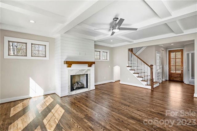 unfurnished living room featuring a premium fireplace, ceiling fan, dark hardwood / wood-style flooring, and beamed ceiling