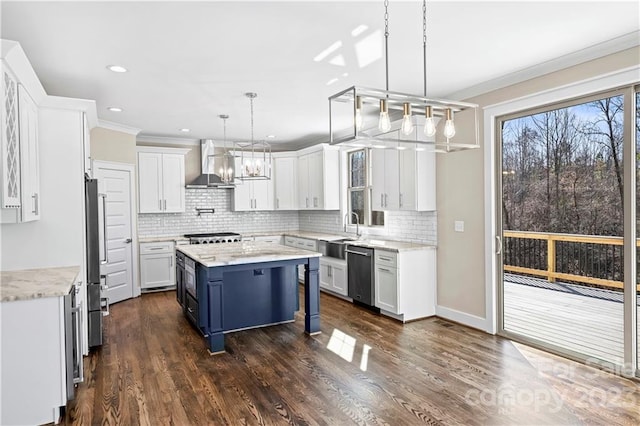 kitchen featuring appliances with stainless steel finishes, wall chimney range hood, dark wood-type flooring, decorative light fixtures, and white cabinetry