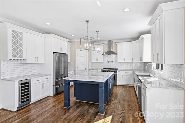 kitchen featuring hanging light fixtures, white cabinets, premium appliances, wine cooler, and wall chimney range hood