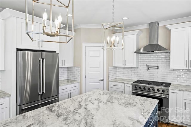 kitchen with white cabinetry, high end appliances, light stone countertops, wall chimney exhaust hood, and backsplash