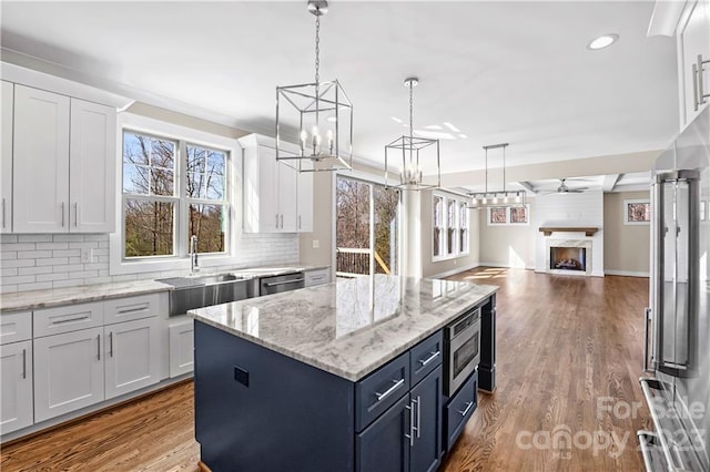 kitchen with pendant lighting, backsplash, white cabinets, and light hardwood / wood-style flooring