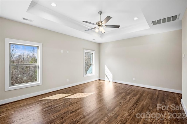 spare room featuring dark hardwood / wood-style floors, ceiling fan, and a tray ceiling