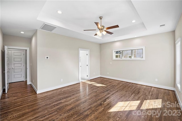 spare room featuring ceiling fan, dark wood-type flooring, and a tray ceiling