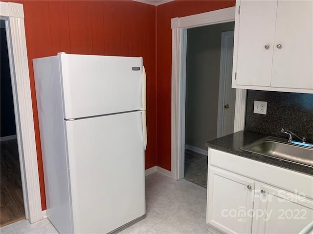 kitchen with white refrigerator, tasteful backsplash, white cabinetry, sink, and light tile flooring