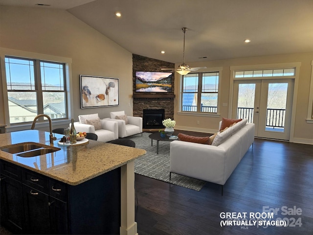 living room with sink, a fireplace, ceiling fan, a healthy amount of sunlight, and dark hardwood / wood-style flooring