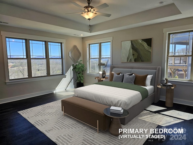 bedroom with ceiling fan, multiple windows, and a raised ceiling