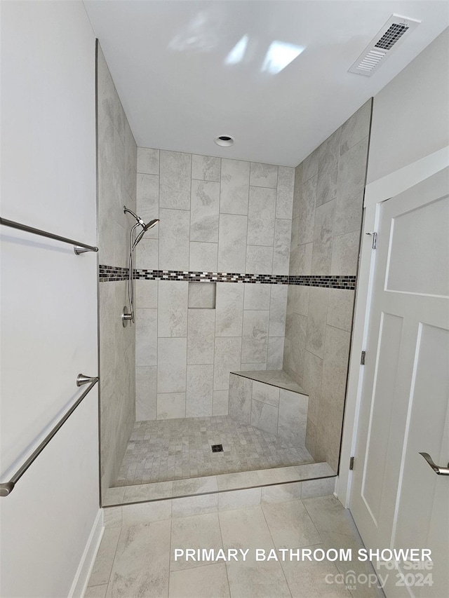 bathroom with a tile shower and tile patterned flooring