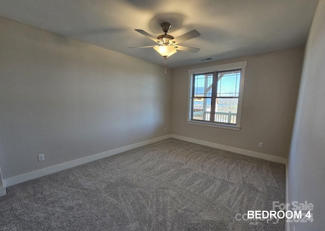 empty room with ceiling fan and dark colored carpet