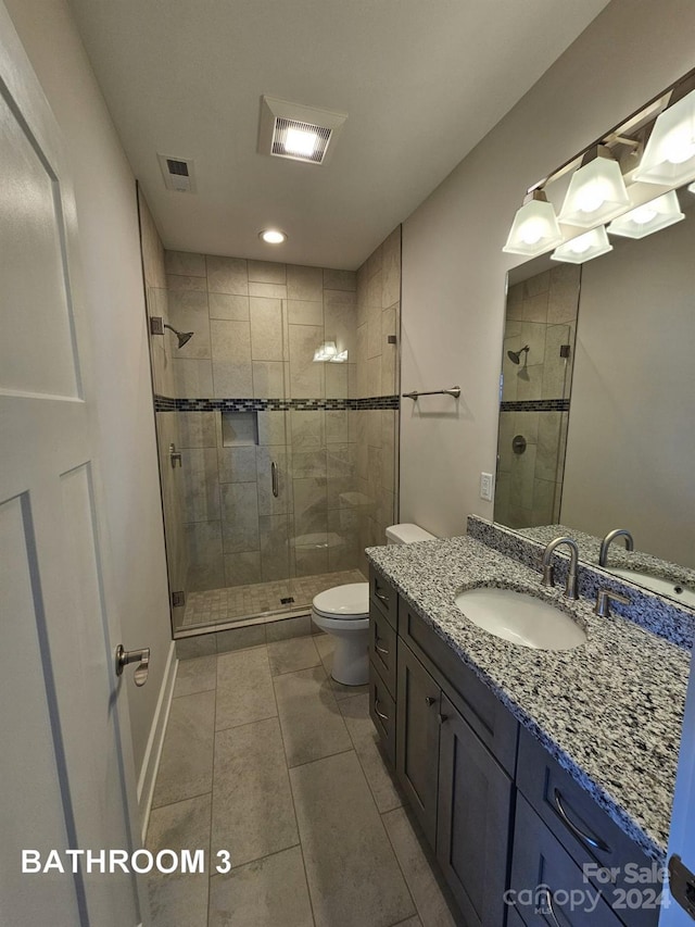 bathroom featuring toilet, an enclosed shower, vanity, and tile patterned floors