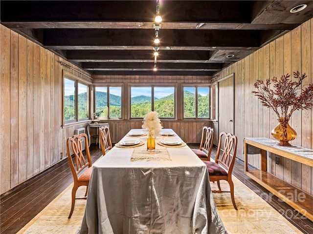 dining area featuring wood walls, a mountain view, dark hardwood / wood-style flooring, and beamed ceiling