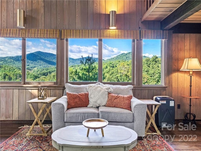 living room featuring wooden walls, dark hardwood / wood-style floors, a mountain view, and beamed ceiling