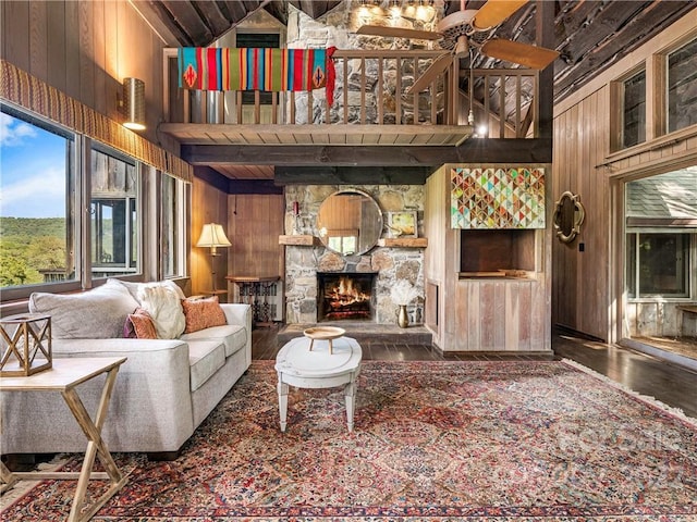 living room with wooden walls, a fireplace, high vaulted ceiling, and dark hardwood / wood-style flooring