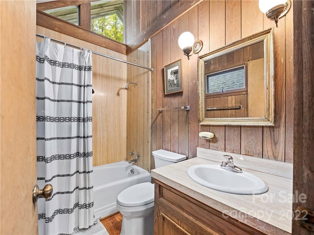 full bathroom featuring wooden walls, shower / bath combination with curtain, large vanity, and toilet