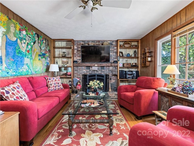 living room featuring a fireplace, wood walls, hardwood / wood-style flooring, and ceiling fan