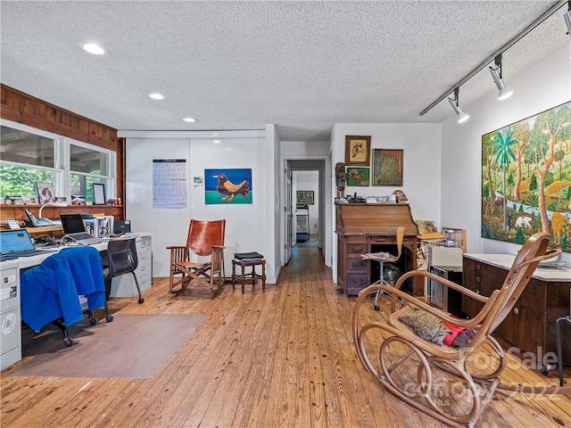 living room featuring a textured ceiling, rail lighting, and light hardwood / wood-style flooring