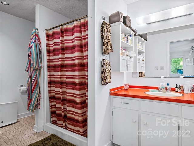 bathroom with a textured ceiling, tile flooring, and vanity