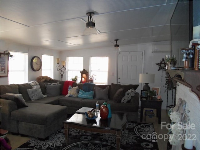 living room with lofted ceiling, plenty of natural light, and a wall mounted air conditioner