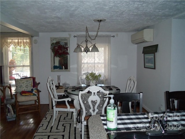 dining area featuring a notable chandelier, dark hardwood / wood-style floors, a wall mounted AC, and a textured ceiling