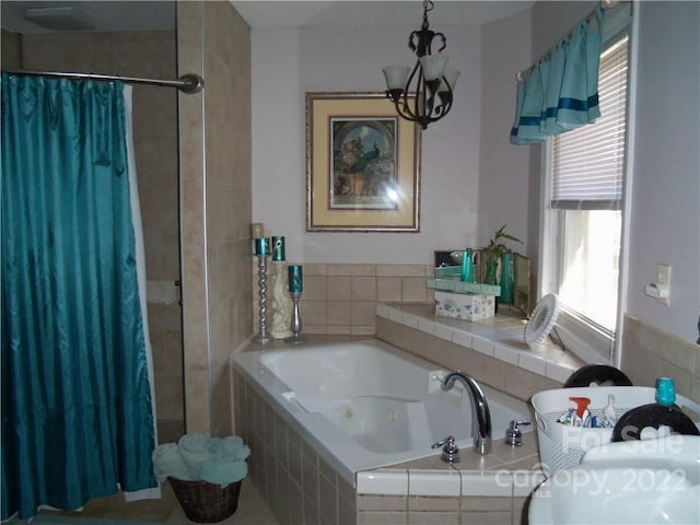 bathroom featuring an inviting chandelier and a relaxing tiled bath