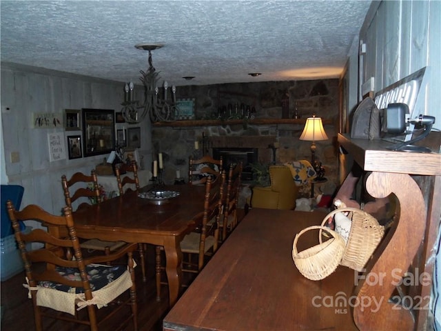 dining area with an inviting chandelier, a textured ceiling, and a fireplace