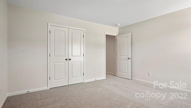 unfurnished bedroom featuring a closet and light colored carpet