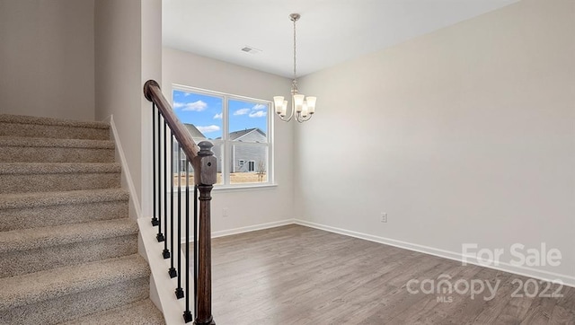 staircase with an inviting chandelier and hardwood / wood-style floors