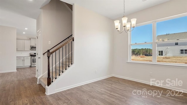 unfurnished room featuring an inviting chandelier and light hardwood / wood-style flooring