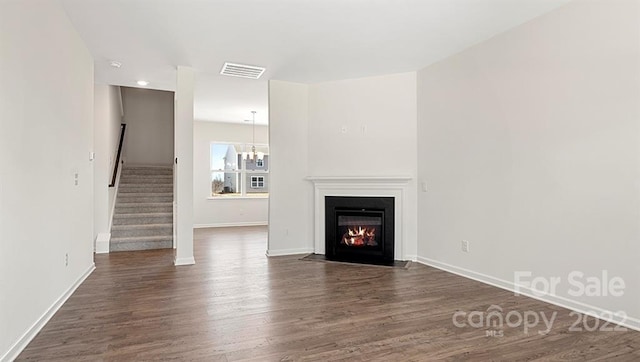 unfurnished living room featuring a notable chandelier and dark wood-type flooring