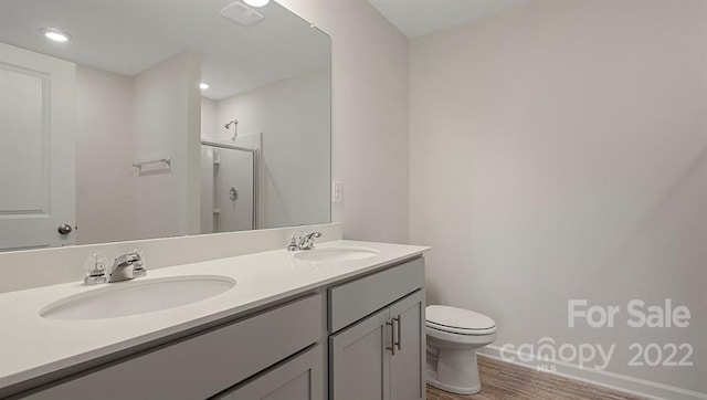 bathroom featuring double vanity, toilet, and hardwood / wood-style floors