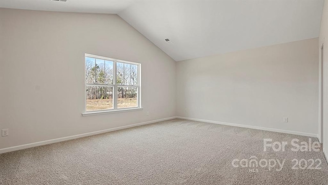 carpeted spare room with lofted ceiling