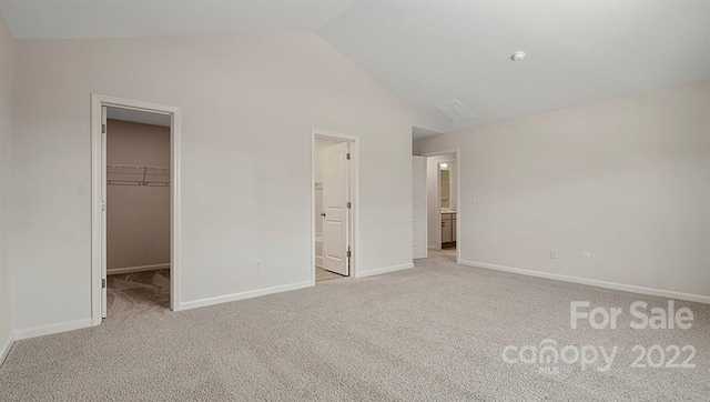 unfurnished bedroom with a walk in closet, light colored carpet, ensuite bath, and a closet