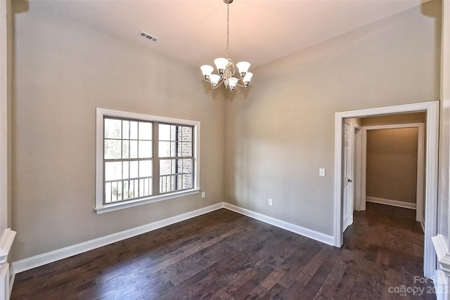 empty room with a notable chandelier, lofted ceiling, and dark wood-type flooring