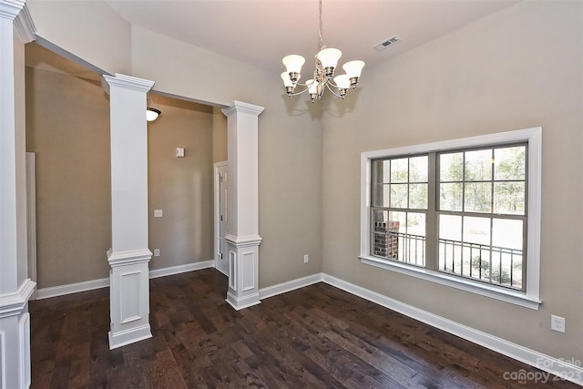 unfurnished room with dark hardwood / wood-style flooring, a notable chandelier, and ornate columns