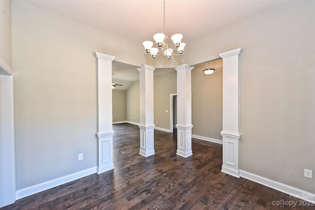 spare room with a notable chandelier, ornate columns, and dark hardwood / wood-style flooring