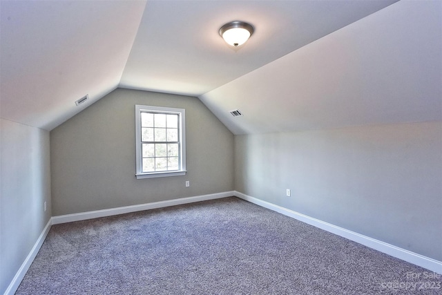 additional living space with vaulted ceiling and dark carpet