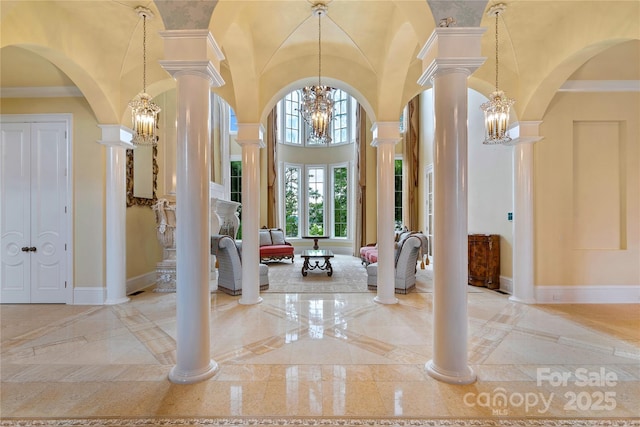 foyer entrance with an inviting chandelier, a towering ceiling, and ornate columns