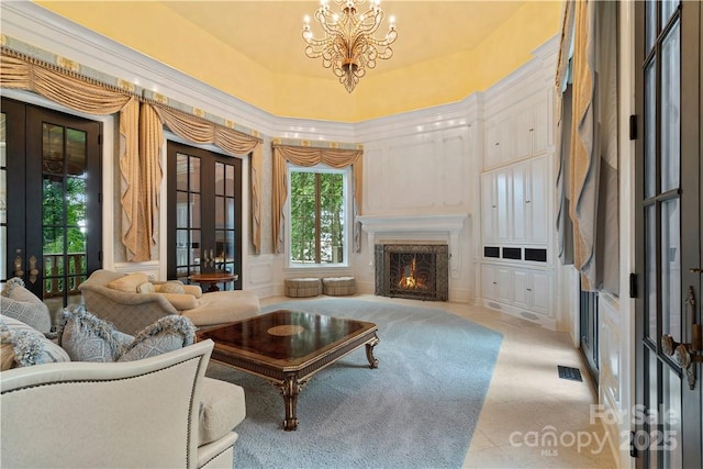 living room with an inviting chandelier, a towering ceiling, a high end fireplace, and french doors