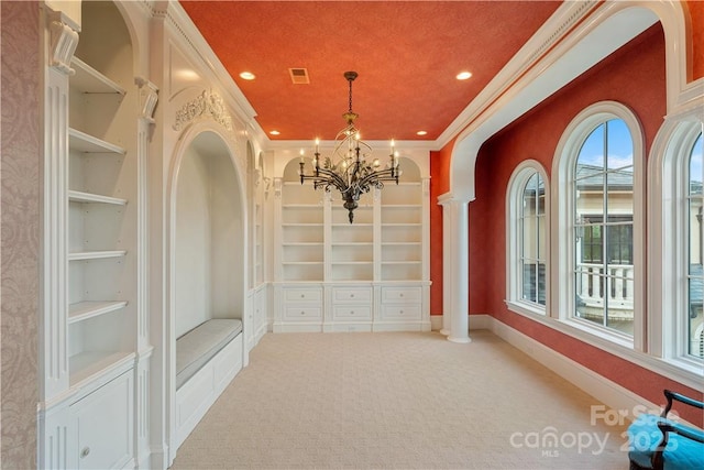 interior space with crown molding, light colored carpet, decorative columns, and built in features