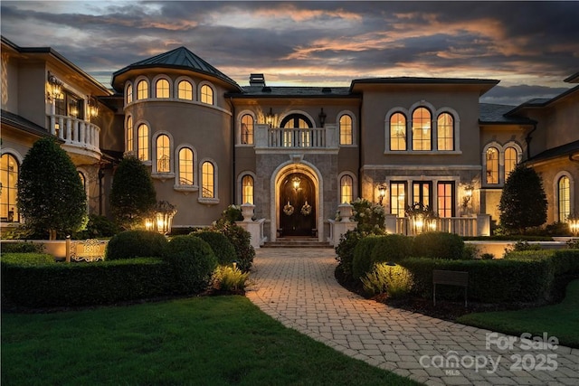 mediterranean / spanish home featuring french doors, a balcony, and a lawn