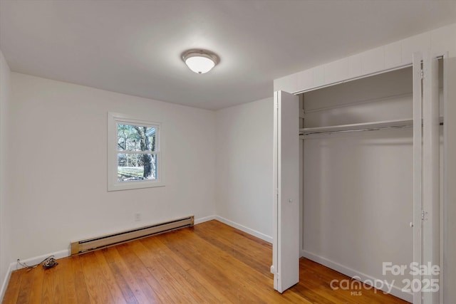 4 Morgan Cove Rd, Candler, NC 28715 - unfurnished bedroom with a baseboard radiator, baseboards, light wood-style flooring, and a closet