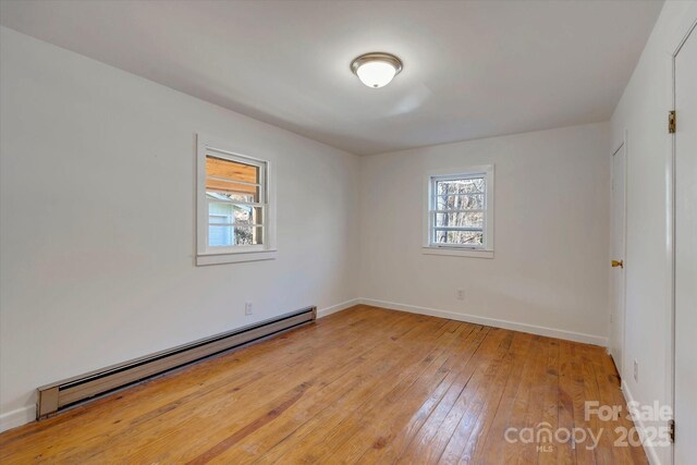 4 Morgan Cove Rd, Candler, NC 28715 - unfurnished room featuring a baseboard heating unit, baseboards, a healthy amount of sunlight, and light wood finished floors