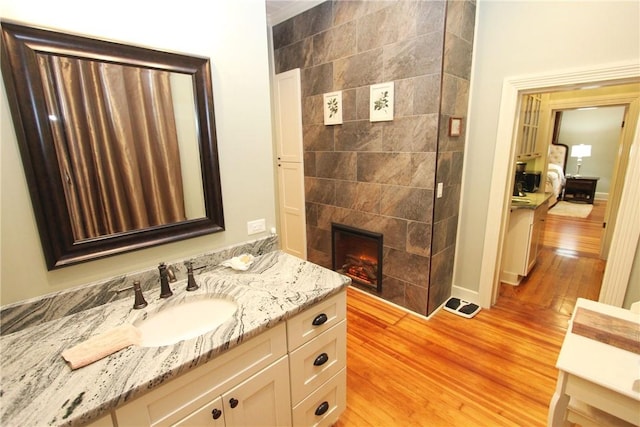 bathroom featuring a tiled fireplace, vanity, and hardwood / wood-style floors