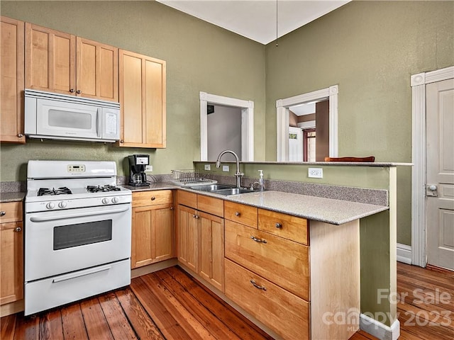 kitchen with sink, white appliances, kitchen peninsula, and dark wood-type flooring