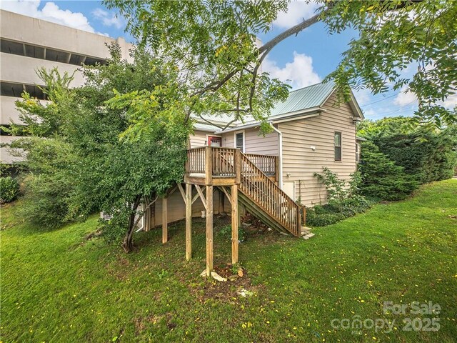 back of property featuring metal roof, a yard, stairs, and a deck
