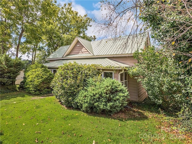 view of side of home with a lawn and metal roof