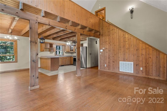 interior space featuring an inviting chandelier, lofted ceiling with beams, stainless steel refrigerator, and light hardwood / wood-style flooring