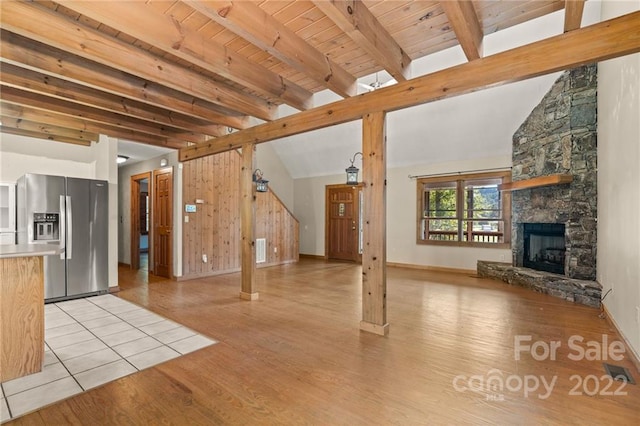 unfurnished living room with wooden ceiling, a fireplace, lofted ceiling with beams, and light hardwood / wood-style floors